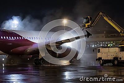Ground deicing of a passenger jetliner on the night airport apron Stock Photo