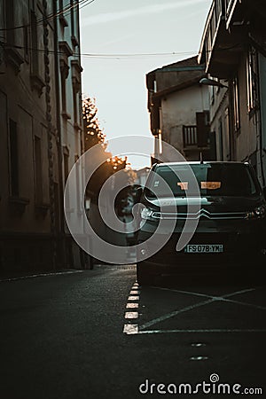 Ground-level shot of a black car in a narrow street in Saint Jean De Luz at sunrise Editorial Stock Photo