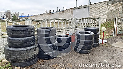 In the ground platform near the tire service station, next to the concrete fence, stacked tires that have fallen into disrepair an Stock Photo