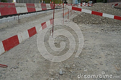 Ground prepared for civil engineering building site bordered by construction barrier planks of red and white color Stock Photo