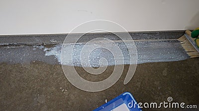 Grounding the floor, preparing the floor for laying mortar. A worker applies a primer to the floor with a brush. Stock Photo