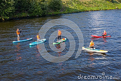 Group of active tourists stand up paddling on sup boards Editorial Stock Photo