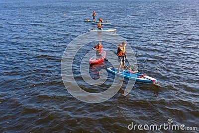 Group of active tourists stand up paddling on sup boards Editorial Stock Photo