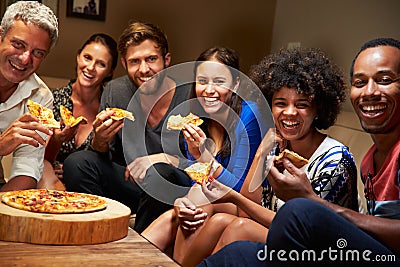 Group of adult friends eating pizza at a house party Stock Photo