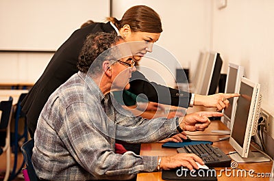 Group of adults learning computer skills. Intergenerational tran Stock Photo