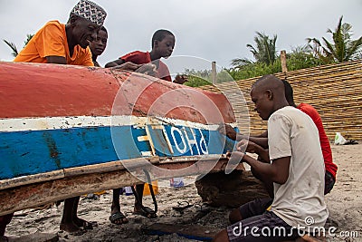 Group of African people fixing and maintaining fisherman's colorful wooden boat, at the shore of Indian Ocean Editorial Stock Photo