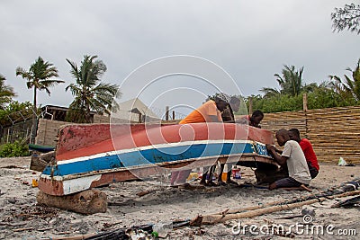 Group of African people fixing and maintaining fisherman's colorful wooden boat, at the shore of Indian Ocean Editorial Stock Photo