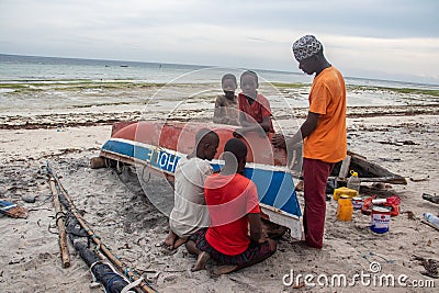 Group of African people fixing and maintaining fisherman's colorful wooden boat, at the shore of Indian Ocean Editorial Stock Photo