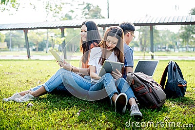 Group of Asian college student using tablet and laptop on grass Stock Photo