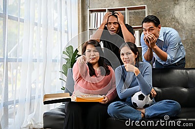 Group of Asian friends football fans watching football or soccer match on TV at home together Stock Photo