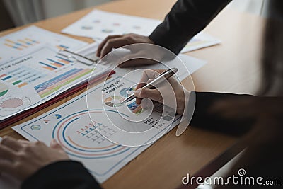 Group Asian Young Businessmen and woman discussing on stockmarket charts at office desk, they are business analyzing. Stock Photo