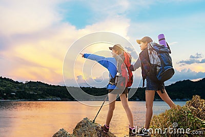 Group asian young women of hikers walking with backpack on a mountain at sunset. Traveler going camping. Stock Photo