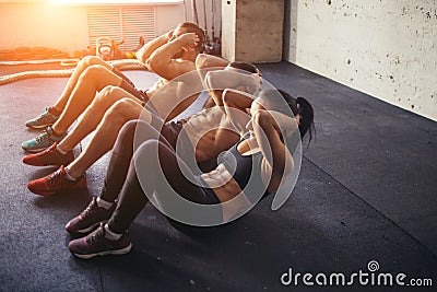 Group of athletic adult men and women performing sit up exercises Stock Photo