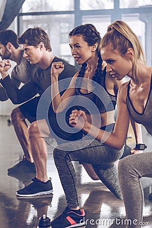 Group of athletic young people in sportswear doing lunge exercise at the gym Stock Photo