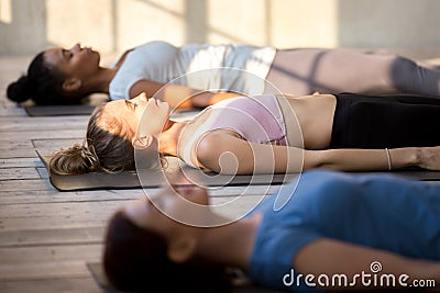 Group of attractive women practicing yoga in Dead Body pose Stock Photo