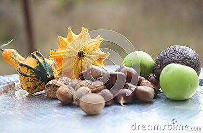 Group of autumnal fruits such as pumpkins, lots of walnuts and chestnuts, green apples and avocado on a silver tray Stock Photo