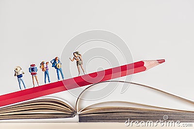 Group of backpackers walking over opened book. Travel concept Stock Photo