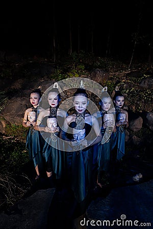 A Group of Balinese woman line up with the wooden mask in their hands while wearing a traditional dance costumes Stock Photo