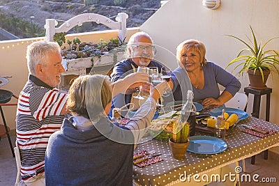 Group of beautiful senior adult have fun and enjoy a dinner outsood on the terrace eating together with smiles and fun. leisure Stock Photo