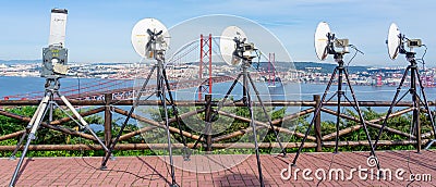 group of broadcast satellite dishes towards Lisbon and 25 de Abril bridge mounted next to the statue of Christ the King of Almada Editorial Stock Photo