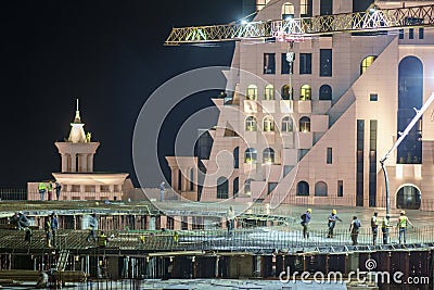 Group of building workers working on illuminated construction site at night Editorial Stock Photo