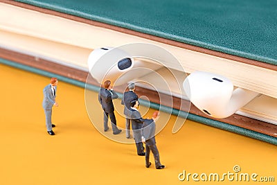 A group of business menâ€™s miniature doll models are studying the headsets on the books Stock Photo