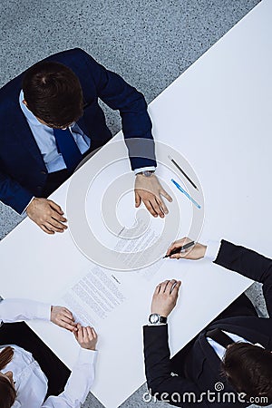 Group of business people and lawyer discussing contract papers sitting at the table, view from above. Businessman is Stock Photo