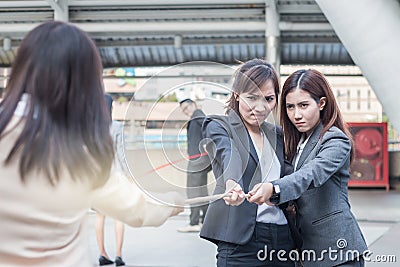 Group of business women pulling a rope competing with commitment to winer Stock Photo
