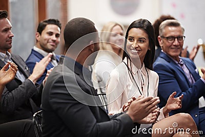 Group Of Businessmen And Businesswomen Applauding Presentation At Conference Stock Photo