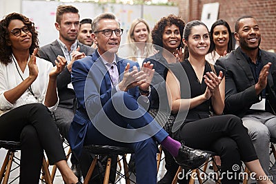 Group Of Businessmen And Businesswomen Applauding Presentation At Conference Stock Photo