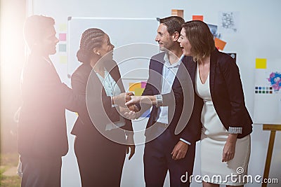 Group of businesspeople shaking hands with each other in front of whiteboard Stock Photo