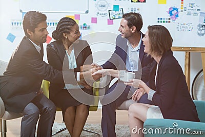 Group of businesspeople shaking hands with each other in front of whiteboard Stock Photo