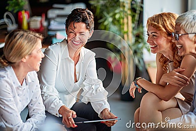 Group of cheerful business women have a good time while talking during a break at workplace. Business, office, job Stock Photo