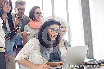 Group of cheerful businesspeople with laptop at desk in creative office Stock Photo