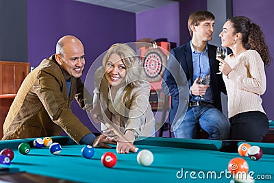 Group of cheerful charming positive friends playing billiards Stock Photo