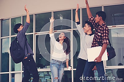 Group of cheerful students with raised hands in the campus, Stu Stock Photo