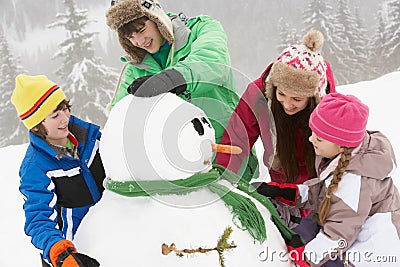 Group Of Children Building Snowman On Ski Holiday Stock Photo