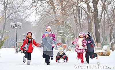 Group of children and mother playing on snow in winter time Stock Photo