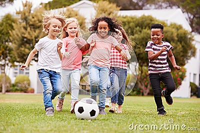 Group Of Children Playing Football With Friends In Park Stock Photo