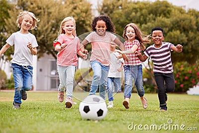 Group Of Children Playing Football With Friends In Park Stock Photo