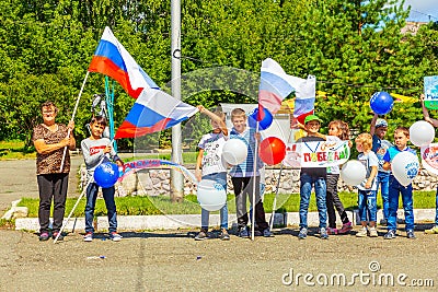 a group of children with Russian flags and sports posters in the park on a summer day. Russian text: Russia Forward, Victory, Hig Editorial Stock Photo