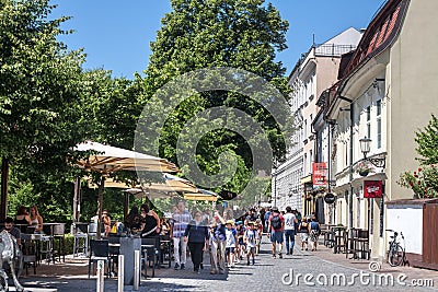 Group of children in schooltrip passing by packed patio of cafe restaurant with people sitting, not respecting social distancing, Editorial Stock Photo