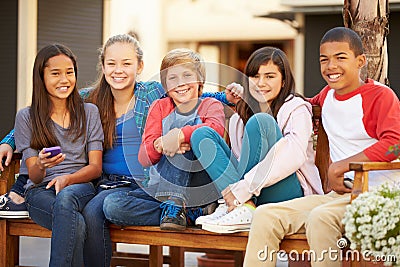 Group Of Children Sitting On Bench In Mall Stock Photo