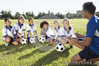 Group Of Children In Soccer Team Having Training With Coach Stock Photo