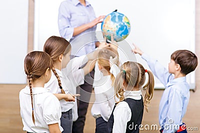 Group of children and teacher holding a globe Stock Photo