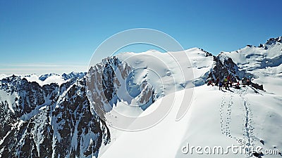 A group of climbers on the tops of a snowy peak. Around the mountain and the blue sky. Stock Photo