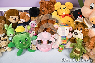 Group of colorful fluffy stuffed animal toys close up in a white wooden baby crib Stock Photo