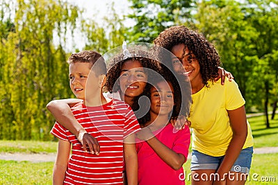 Group of cool diverse kids hug in park together Stock Photo