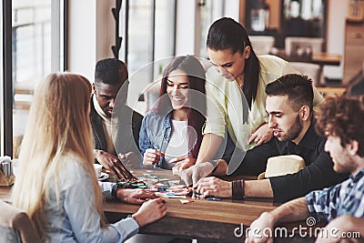 Group of creative friends sitting at wooden table. People having fun while playing board game Stock Photo