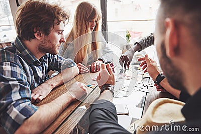 Group of creative multietnic friends sitting at wooden table. People having fun while playing board game Stock Photo